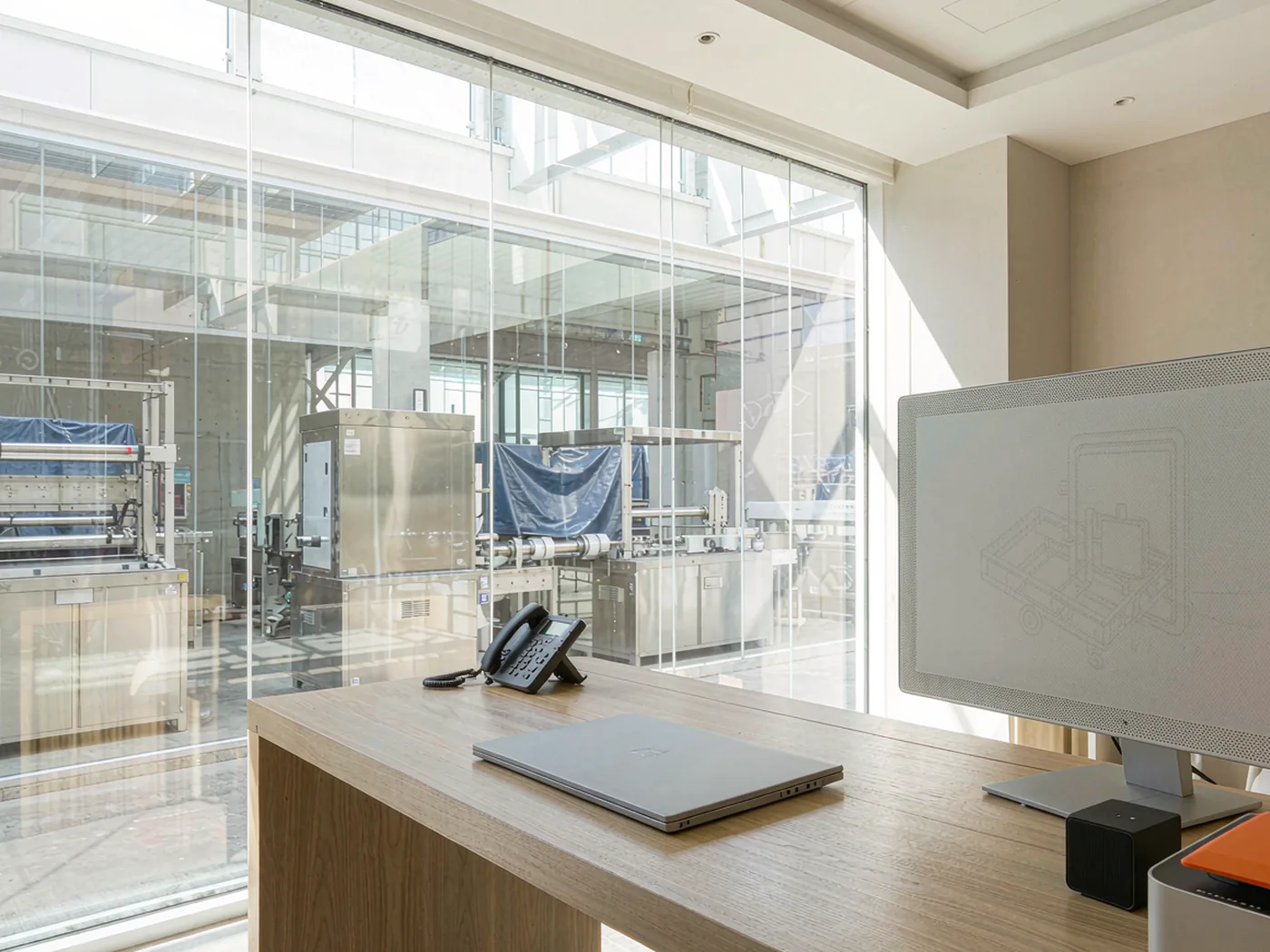 Bright modern office reception overlooking a packaging machinery factory hall